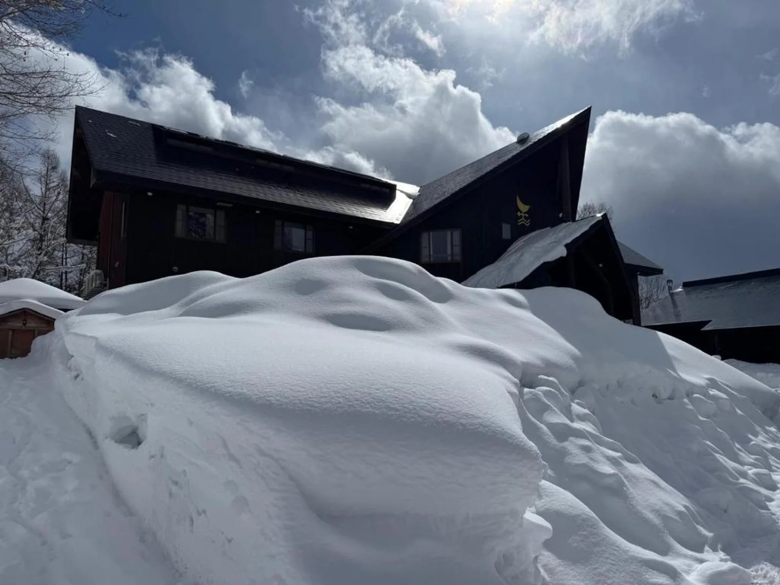 The lodge behind a deep bank of fresh snow under a clearing sky